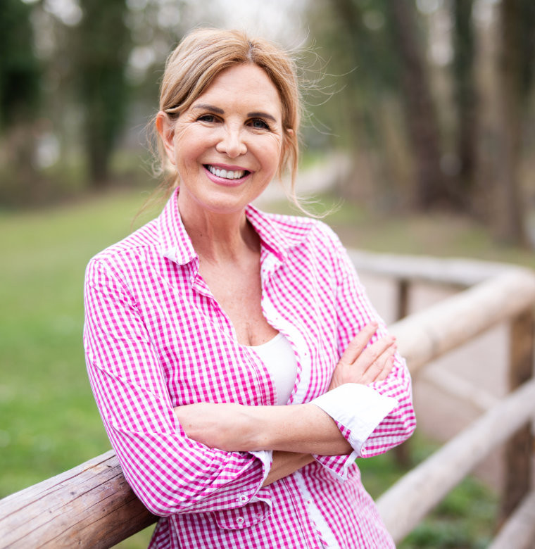 Frau lehnt entspannt am Geländer im Park – steht für selbstbestimmte Ruhestandsplanung und finanzielle Sicherheit im Alter.